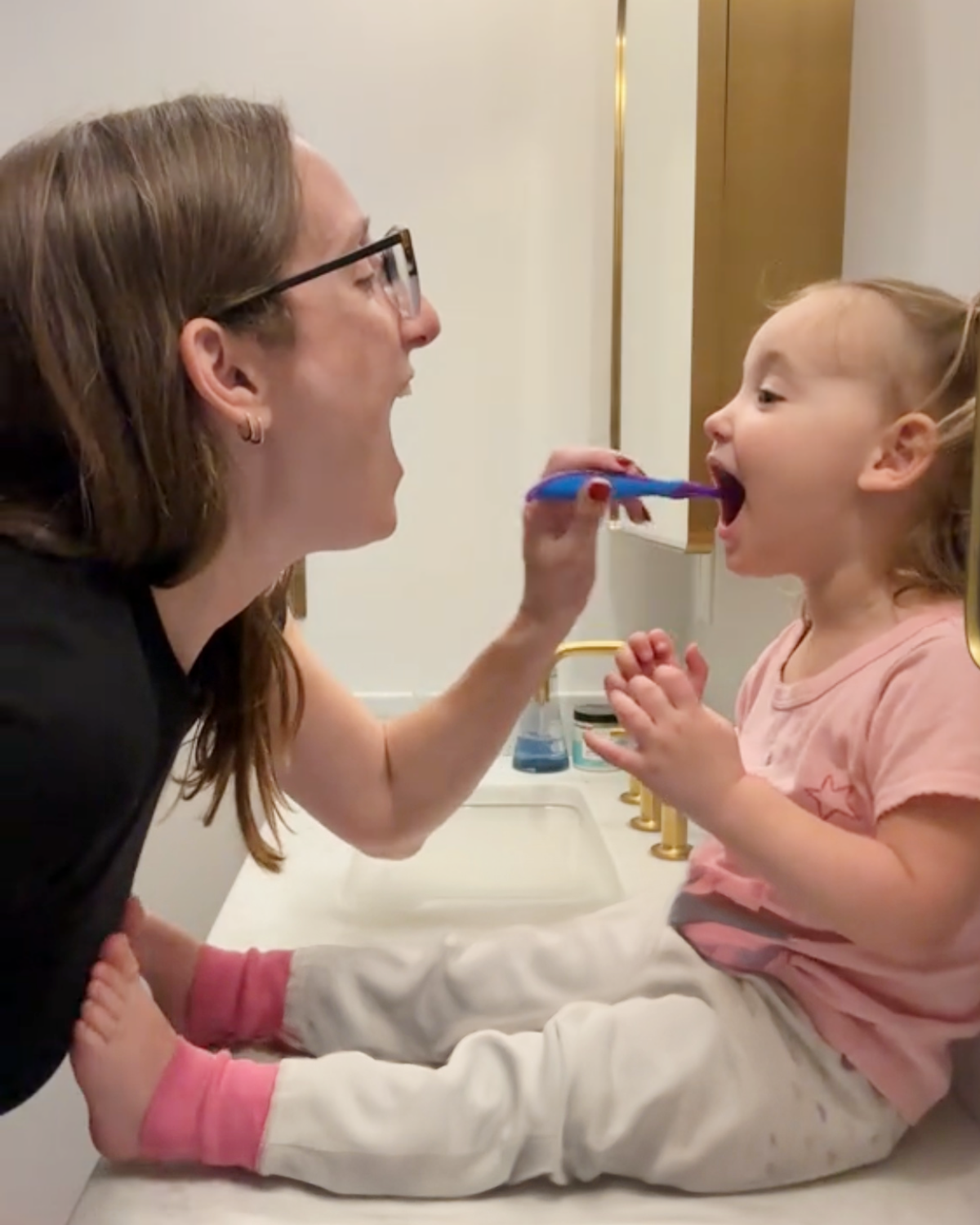 Carley with her daughter, brushing in the bathroom