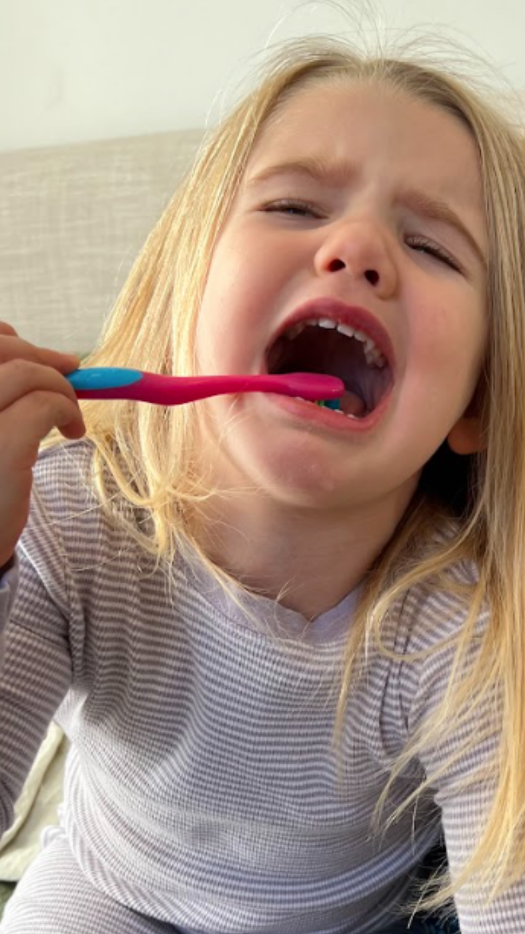 kid resisting toothbrush, mouth open